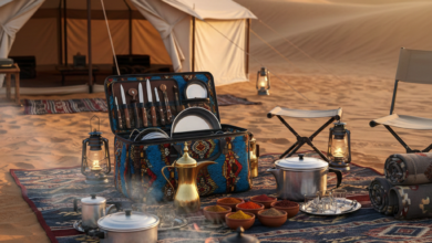عزبة طبخ احترافية مفتوحة تعرض أدوات الطبخ المنظمة في الصحراء السعودية مع دلة قهوة عربية وخيمة في الخلفية عند غروب الشمس